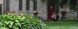 Woman sitting outside building with flowers.