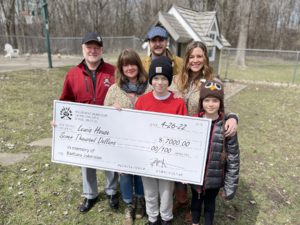 Family holding a check for Lewis House.