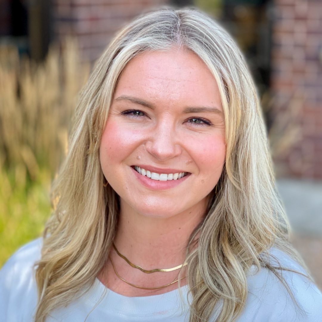 Smiling woman with blonde hair and a necklace.